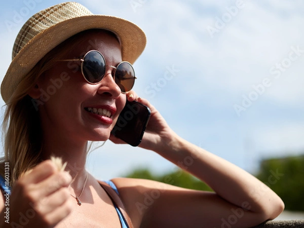 Fototapeta Attractive female traveler is talking on mobile phone.