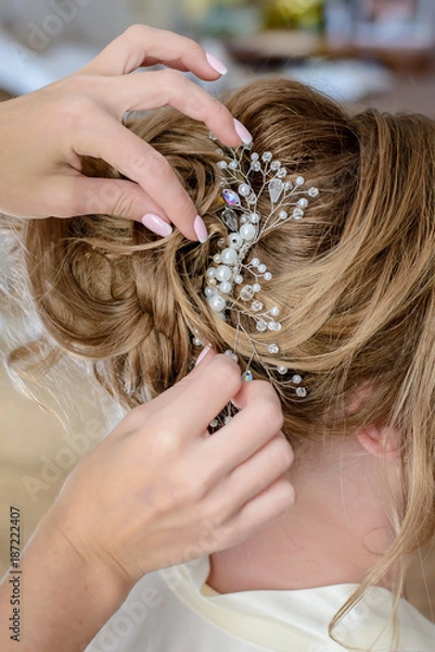 Fototapeta Hairdresser makes a wedding hairstyle with a beautiful decoration