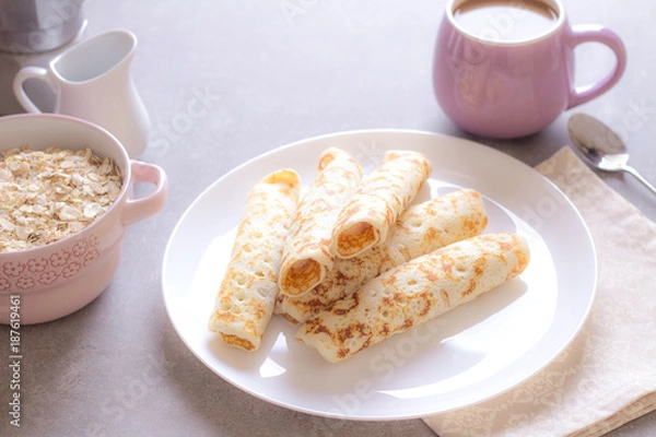 Fototapeta Homemade crepes with cream soft cheese on white plate, cup of coffee. Sunny morning. Delicious breakfast.