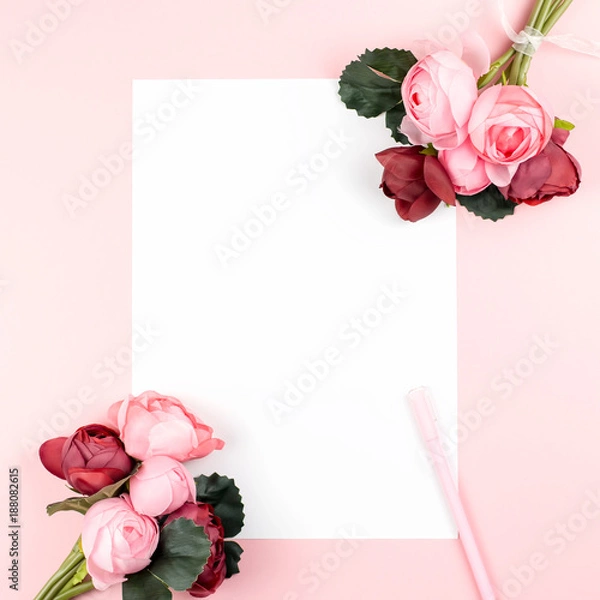 Fototapeta Blank paper card with pen, red and pink flowers frame on pastel background, copy space.