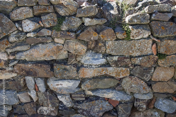 Fototapeta Old stone wall closeup texture, invaded by moss, weathered, a rustic wall in Spain`s countryside