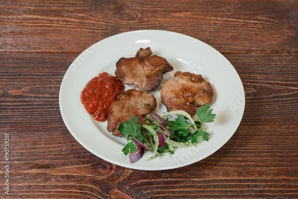 Fototapeta Roasted pork neck on a plate. Appetizing dish on the wooden brown table.