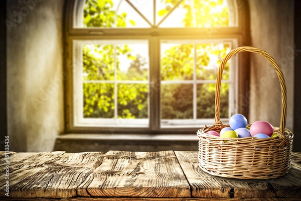 Fototapeta Easter eggs on wooden table in basket and background of window of spring. 