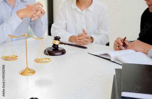 Fototapeta Judge gavel with Justice  lawyers having team meeting at law firm in background. Concepts of law.