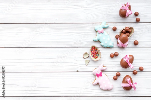 Obraz Celebrate Easter. Modern signs of Easter. Chocolate Easter eggs and Easter bunny cookies. White wooden background top view copy space