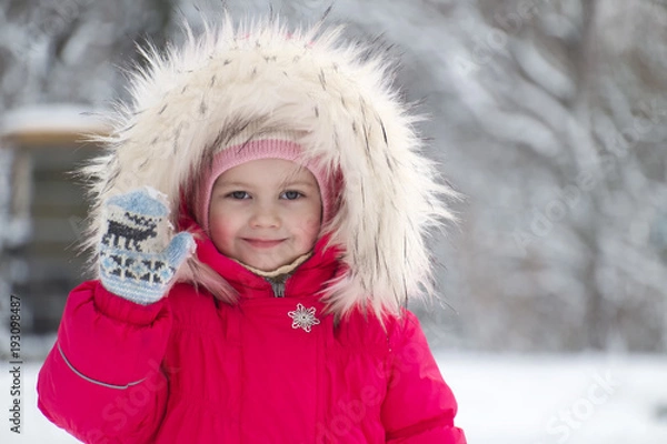 Fototapeta Little cute girl in a big fur hood waving her hand