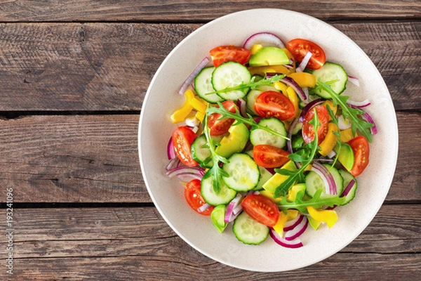 Fototapeta Healthy vegetarian dish, vegetable salad with fresh tomato, cucumber, bell pepper, red onion, avocado and arugula