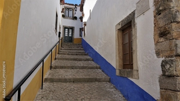 Fototapeta A colorful Street in the medieval town of Obidos, Portugal. Obidos is a city with history and culture. It combines the middle ages and the present one. Photos filmed on 19.09.2015 year.