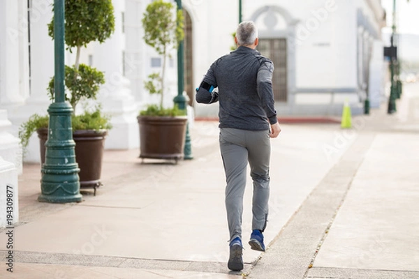 Fototapeta Mature man on a morning run in the city