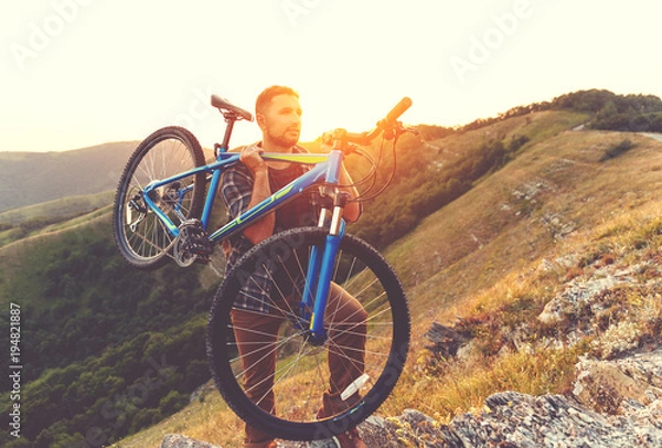 Fototapeta cycling. young man with bicycle on nature in mountains