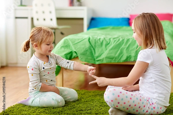 Fototapeta girls playing rock-paper-scissors game at home