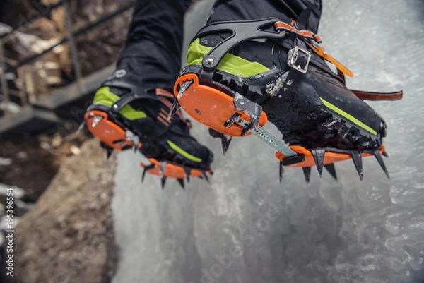 Fototapeta Climber on a frozen waterfall. Crampons close-up on his feet ice climber