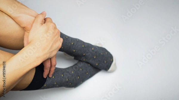 Fototapeta Sits and Hugs the knees up to the chest, wearing sock on white background