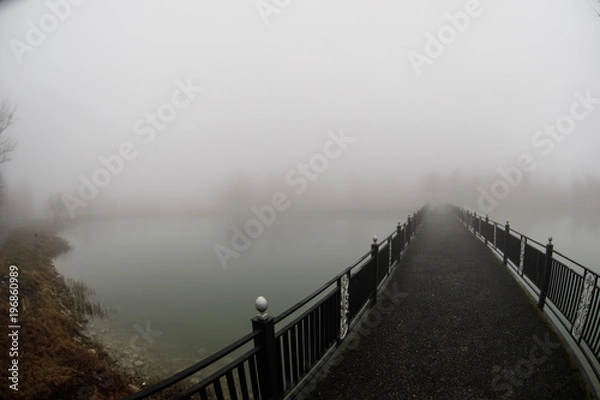 Obraz Amazing landscape of bridge reflect on surface water of lake, fog evaporate from pond make romantic scene or Beautiful bridge on lake with trees at fog.