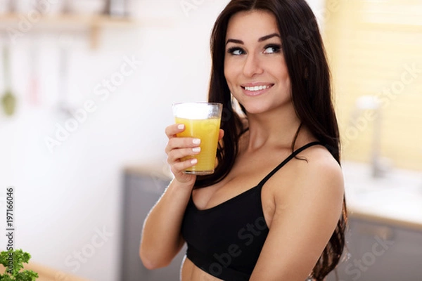 Fototapeta Fit smiling young woman with healthy juice in modern kitchen