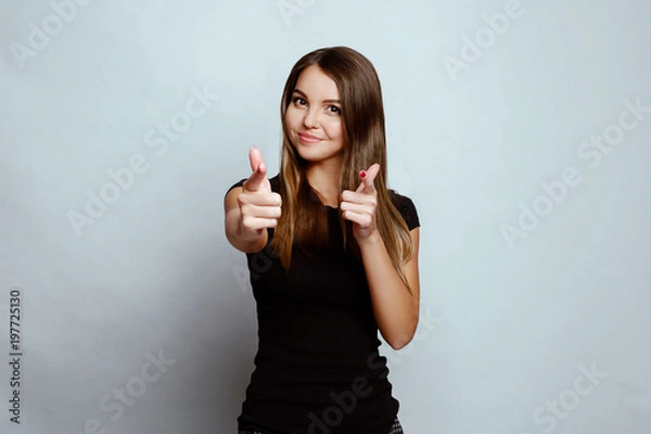 Fototapeta Positive emotions and feelings on white background.Caucasian female with long hair, wearing black T-shirt,pointing with her index fingers at you and smiled