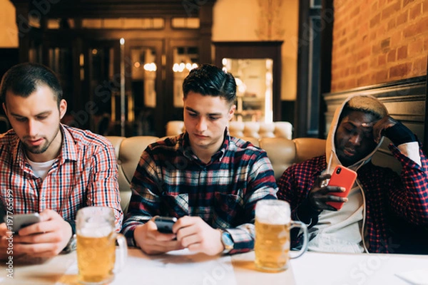 Fototapeta Men's friends with smartphones drinking beer at bar or pub