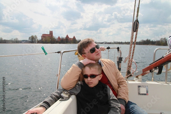 Fototapeta Father and son have a trip in sailboat on a lake by Trakai castle in Lithuania