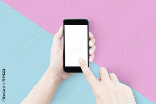 Fototapeta Hands using smartphone over pastel pink and light blue background.