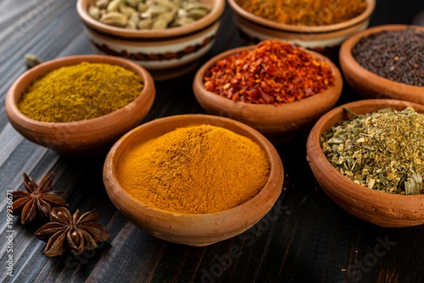 Fototapeta Different colorful spices in  spoons  on a dark  background.