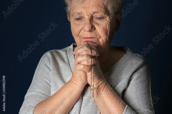 Fototapeta Religious elderly woman praying on dark background