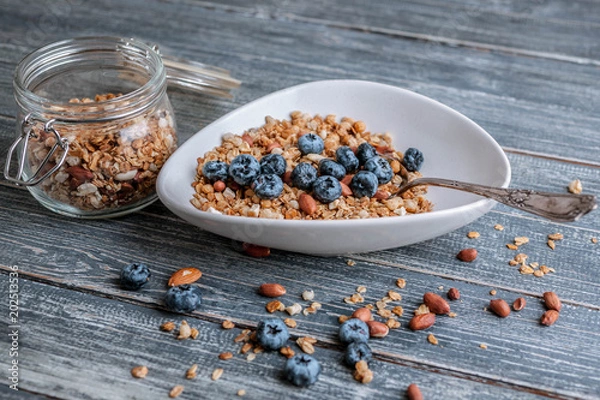 Fototapeta Muesli or granola in a bowl with a spoon, blueberries and nuts. Top view. Healthy breakfast