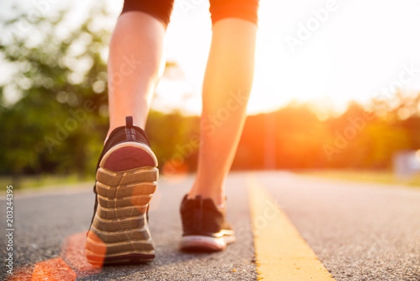 Fototapeta Healthy lifestyle sports woman legs running and walking  while exercising outdoors during sunrise or sunset. Moving forward to success concept.