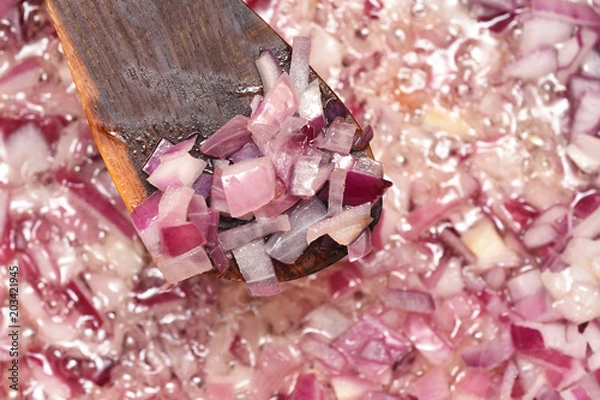 Fototapeta Chopped fresh onion is fried in a frying pan with oil. Close-up