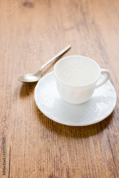 Fototapeta white coffee cup with coffee stains next to spoon and on wooden background