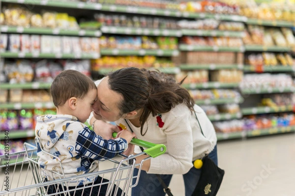 Fototapeta Mom gently kisses his young son in the supermarket