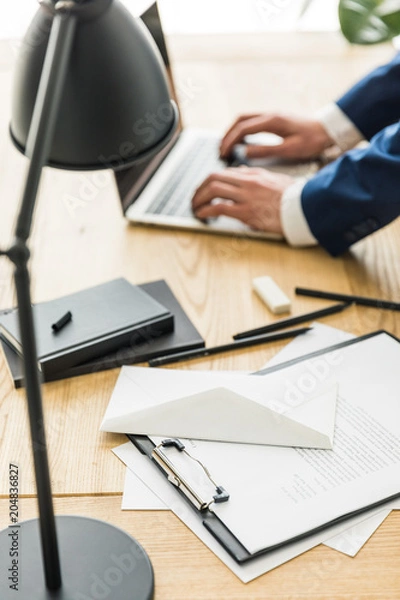 Fototapeta selective focus of businessman working on laptop at workplace in office