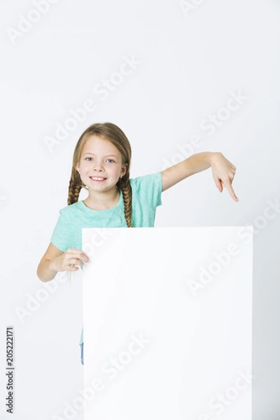 Fototapeta pretty, brunette girl is pointing at white board in front of white background