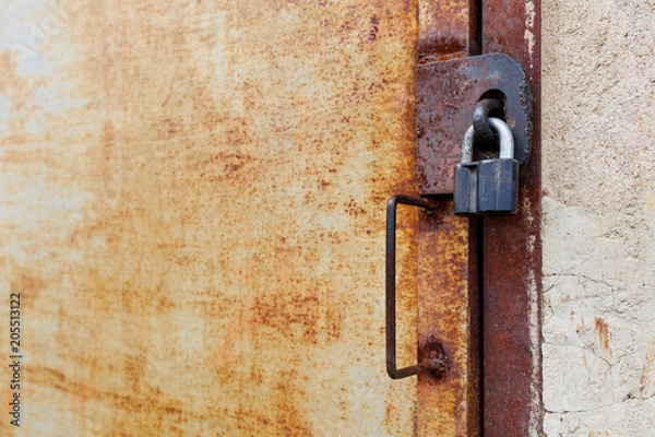 Fototapeta old rusty iron door with padlock and handle, side view close-up