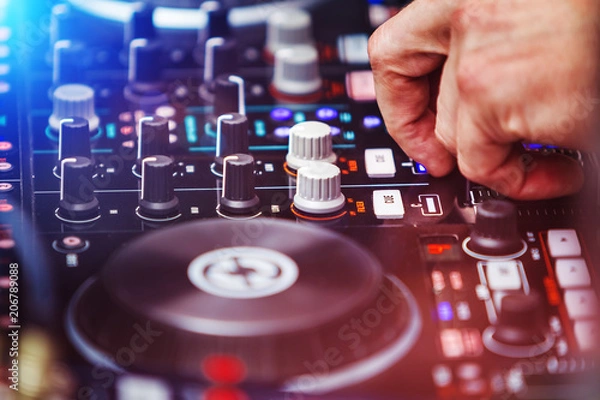 Fototapeta closeup hands of DJ pushing buttons at the professional console. disc jockey playing at night club. EDM, party clubbing life concept