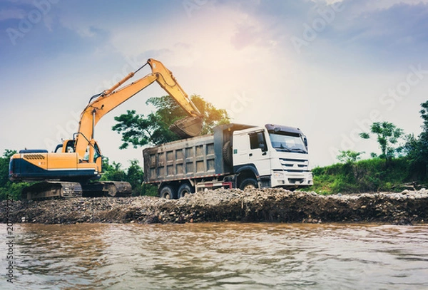 Fototapeta Tracked excavator loading soil and stone in a truck