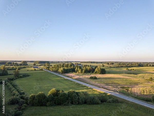 Fototapeta drone image. asphalt road surrounded by pine forest and fields from above