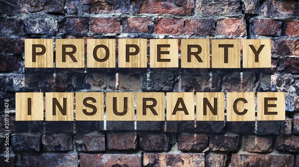 Fototapeta Words, property insurance, consisting of letters on wooden construction cubes against the background of an old vintage brick wall. Concept business