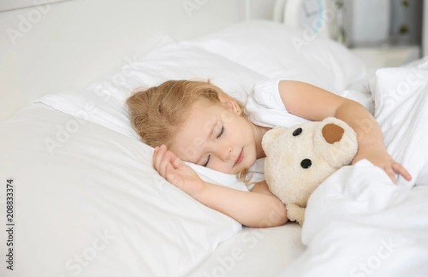 Fototapeta Cute little girl sleeping with toy in bed