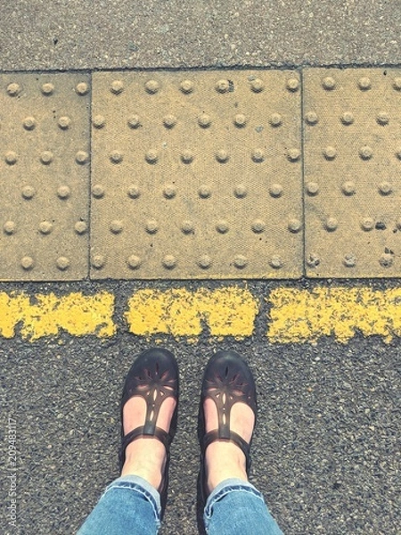 Fototapeta Standing behind the yellow line with sandals