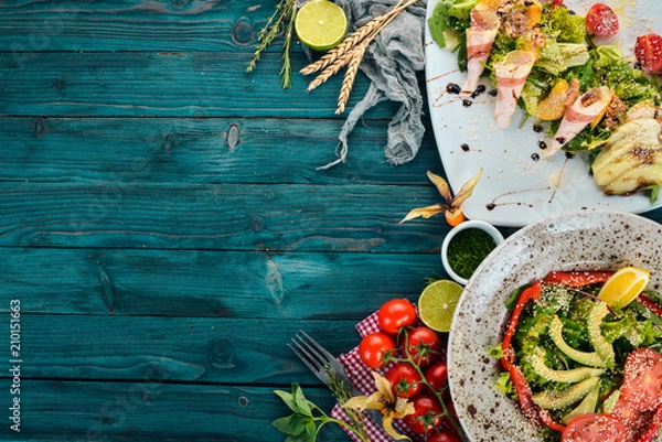 Fototapeta Food. A set of delicious salad with avocado and vegetables. On a wooden background. Top view. Copy space.