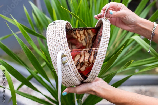 Fototapeta Fashionable stylish rattan bag outside. Tropical island of Bali, Indonesia. Rattan handbag.