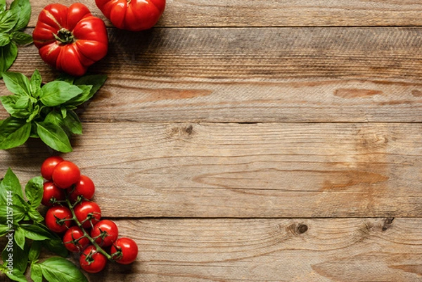 Fototapeta Tomatoes and basil on wood background, cooking ingredients. Food background, pizza or picnic background with copy space for text