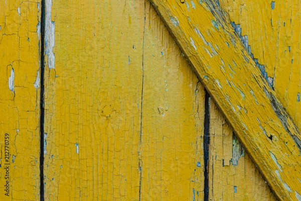 Fototapeta Background of old wooden boards with cracked yellow paint.