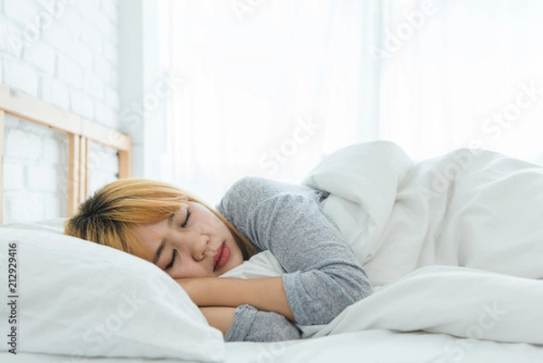 Fototapeta Beautiful young Asian woman sleeping in bed in the morning. Attractive asian girl use bedtime in her comfortable bedroom. Relaxation bedroom. Iifestyle asia woman at home concept.