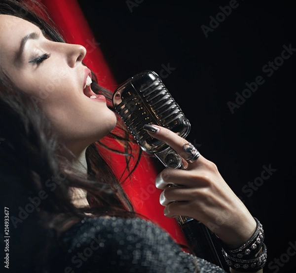 Fototapeta Portrait of beautiful woman singing in microphone