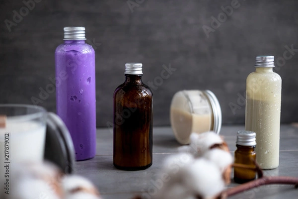 Fototapeta Bottles with natural spa cosmetic products on dark gray concrete table. Beauty blogger, salon treatments, minimalism concept