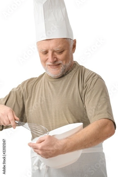 Fototapeta Senior chef whisking egg in kitchen