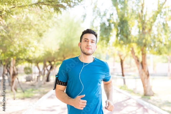 Fototapeta Athletic Male Listening Music While Running In Park