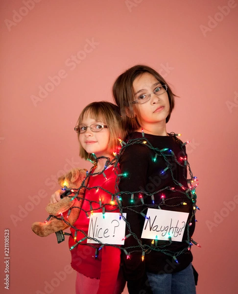 Fototapeta Kids wrapped up in Christmas lights for the holidays Naughty and Nice Concept