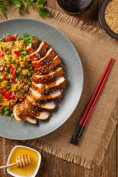 Fototapeta Grilled chicken breast in teriyaki sauce. Served with brown rice and vegetables.